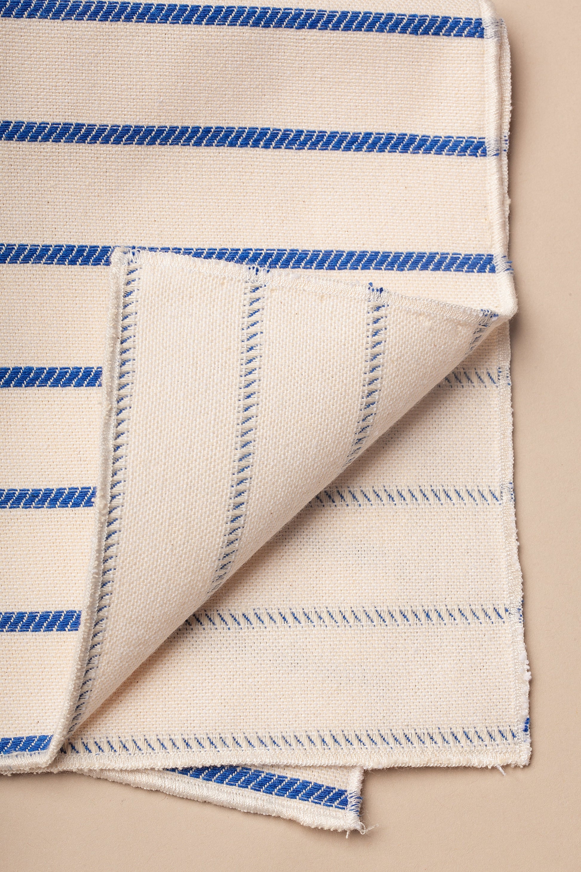 Tela de algodón beige con rayas azul marino, ideal para decoración y manualidades.