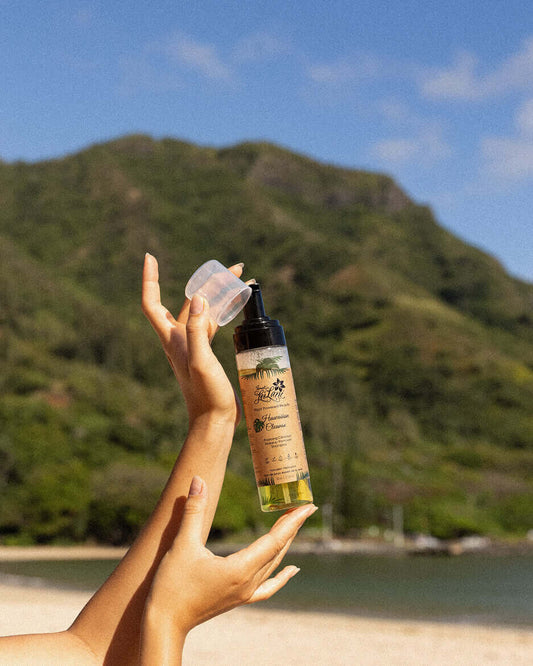 Hawaiian Cleanser | Makeup Remover and More held in hands against a tropical beach background, showcasing its natural essence.