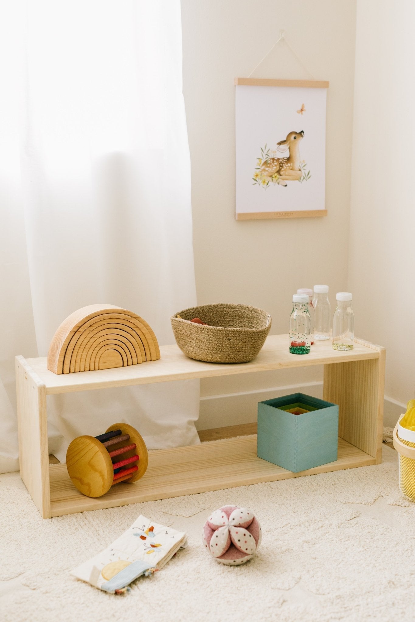 Estantería de madera natural con juguetes coloridos y una cesta de mimbre, ideal para la habitación infantil.