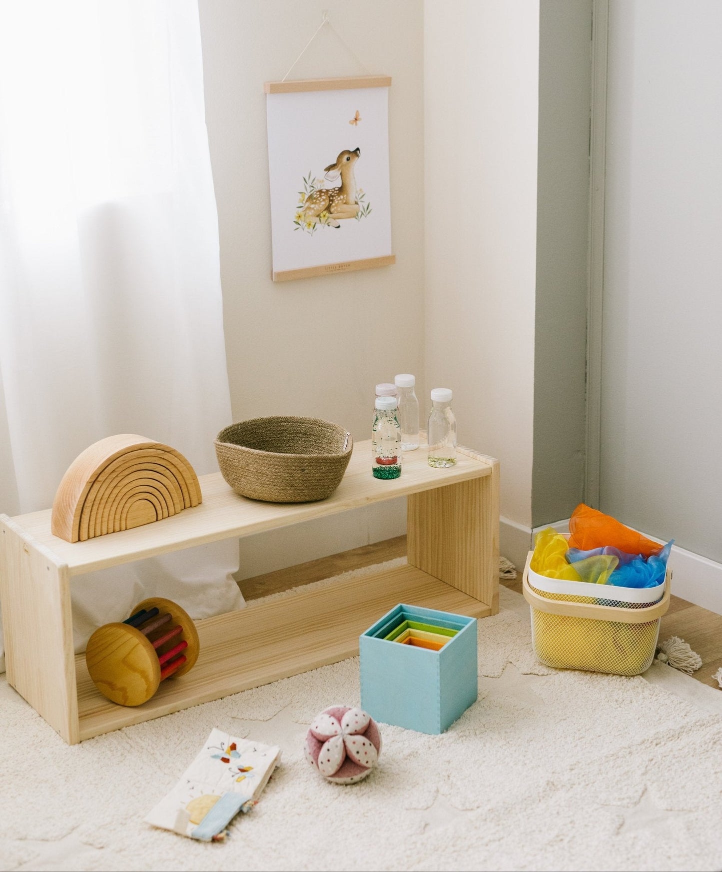 Estante de madera natural con juguetes de colores, canasta tejida y decoración infantil en una habitación luminosa.