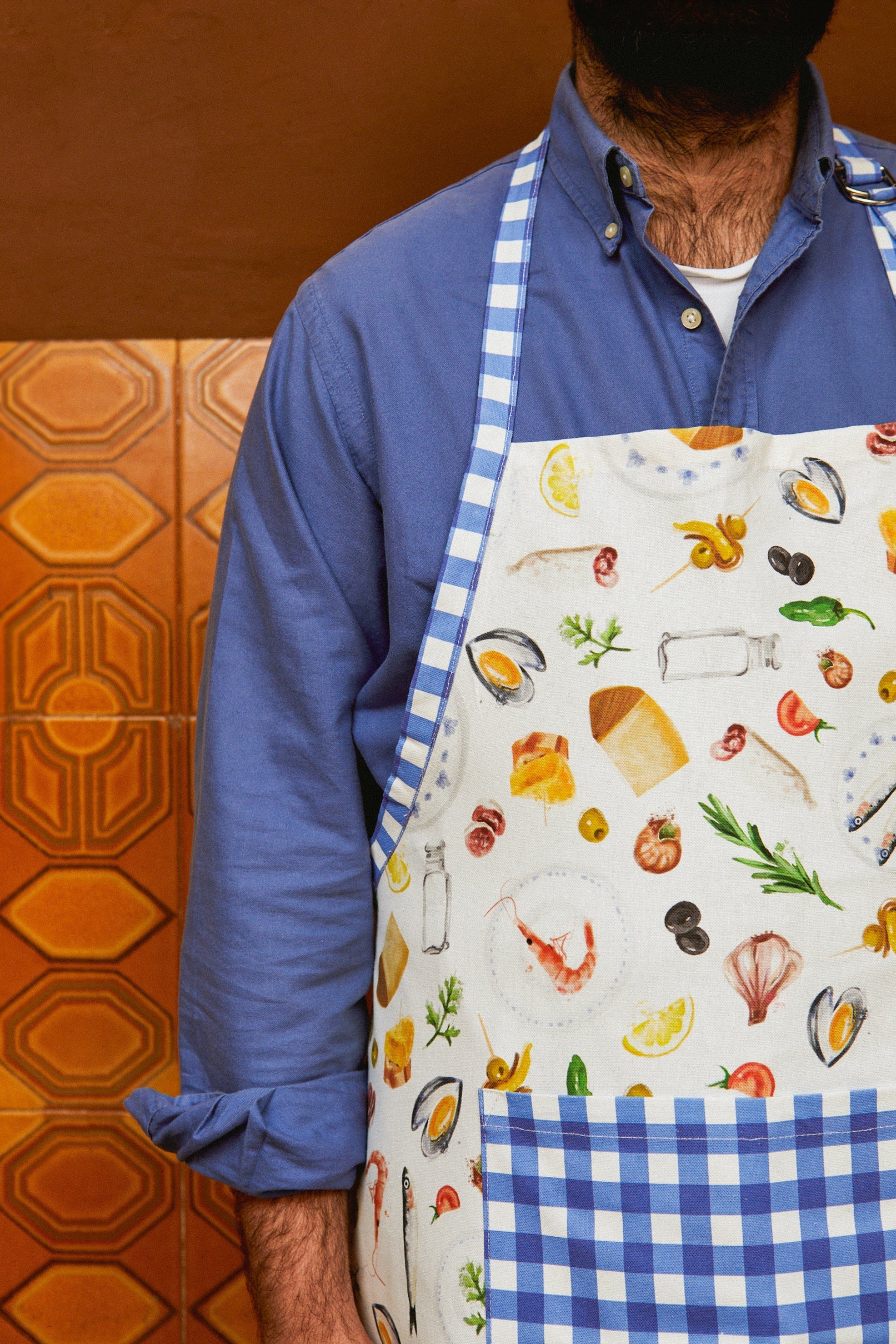 Delantal de cocina blanco con estampado marino, bordes a cuadros azules, ideal para chefs y amantes de la gastronomía.