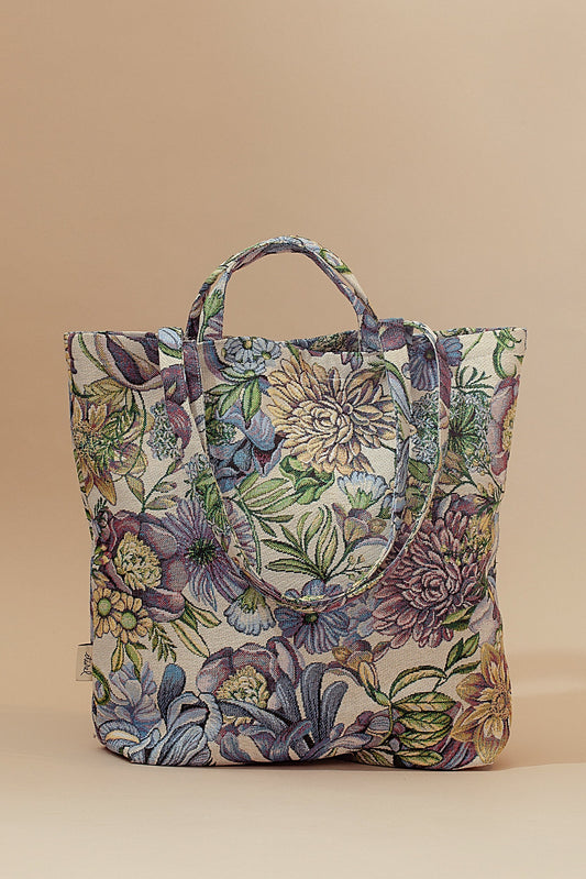 Tote bag de tela jacquard con estampado de crisantemos y flores en tonos azules, morados y verdes sobre fondo crema.