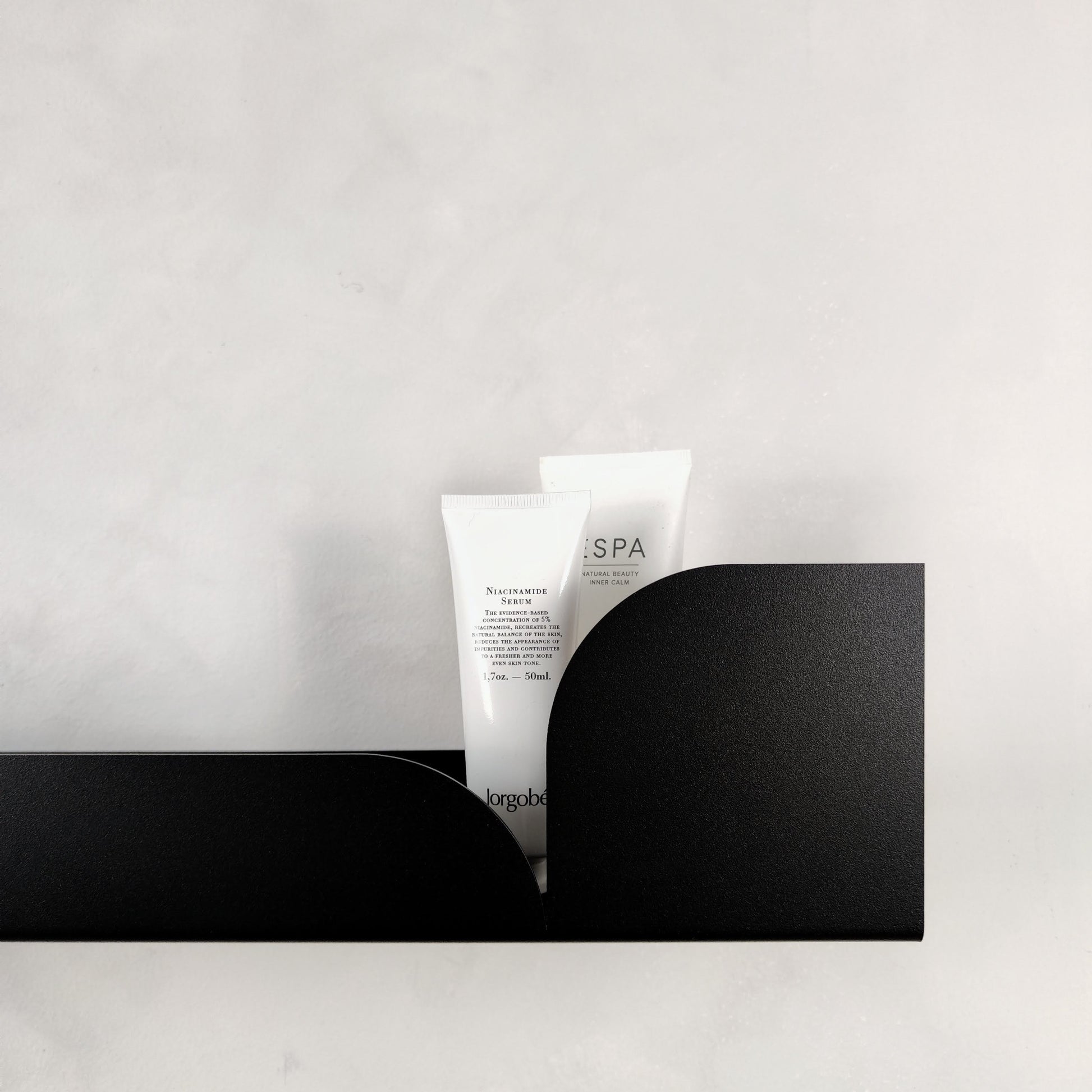 Estantería metálica mediana Torino con productos de spa sobre un fondo claro.