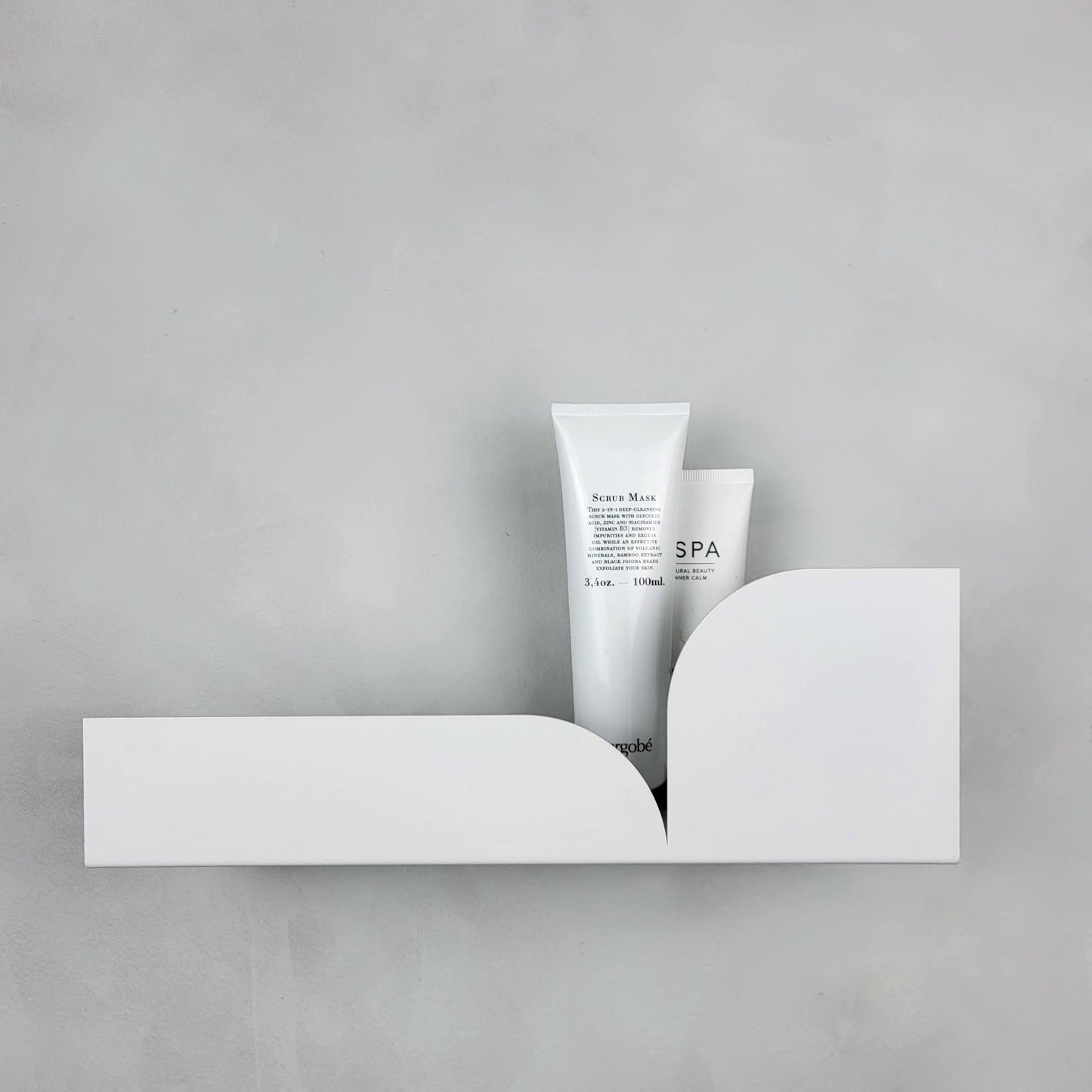 Estantería metálica mediana Torino con productos de spa decorando una pared moderna.