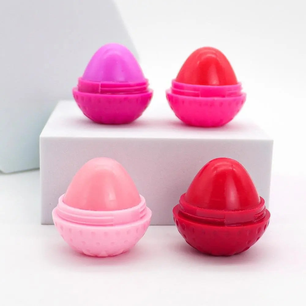 Four round, strawberry-shaped lip butter pods in shades of pink and red on a white display block.