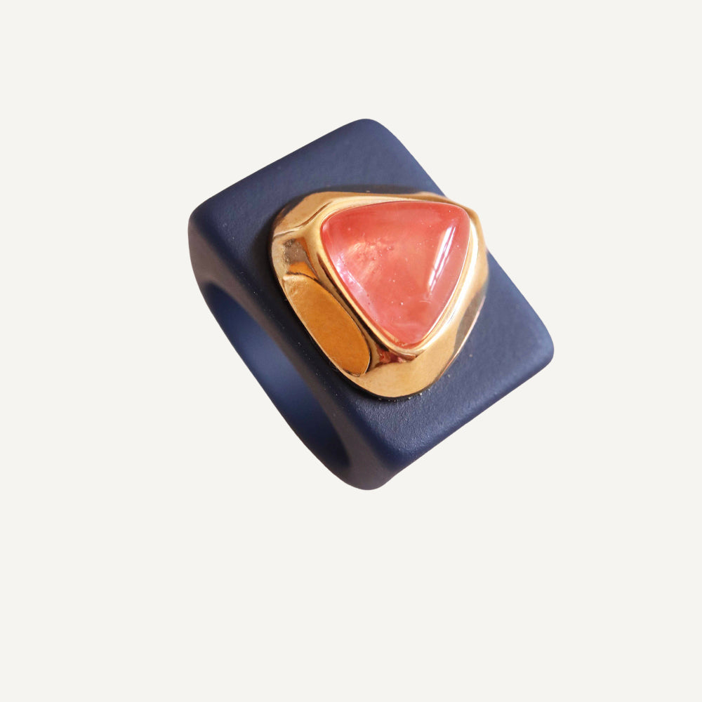 Anillo cuadrado negro con piedra triangular rosa y acabado dorado. Ideal para un estilo moderno y elegante.