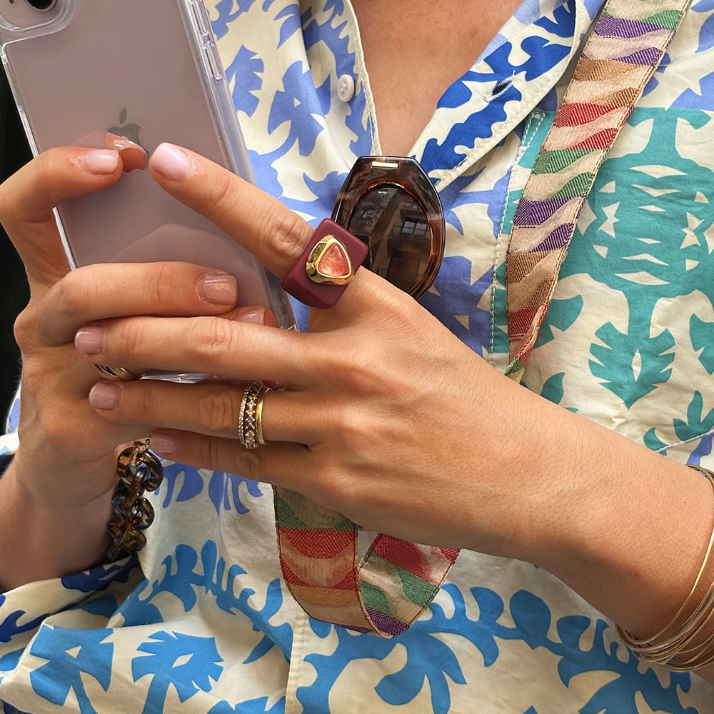 Anillo grande de resina morado con detalle dorado, estilo moderno, ideal para combinar con blusas coloridas.