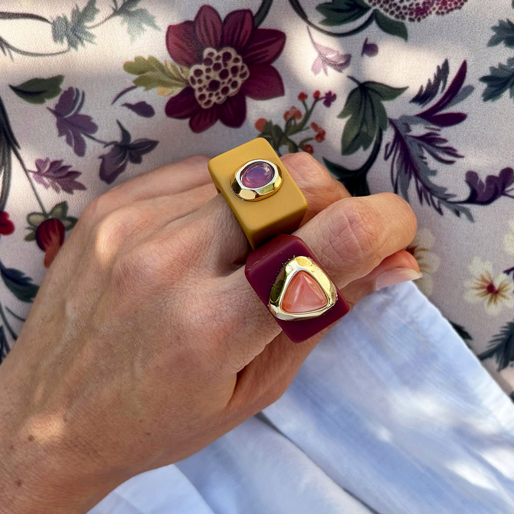 Anillos modernos de resina en amarillo y burdeos con detalles dorados y piedras preciosas, estilo elegante y vibrante.