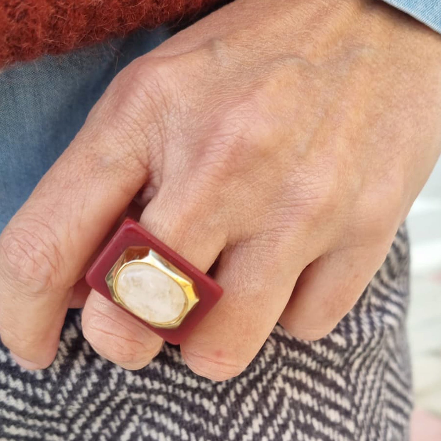 Anillo cuadrado de resina roja con piedra clara y detalles dorados, estilo moderno y elegante.