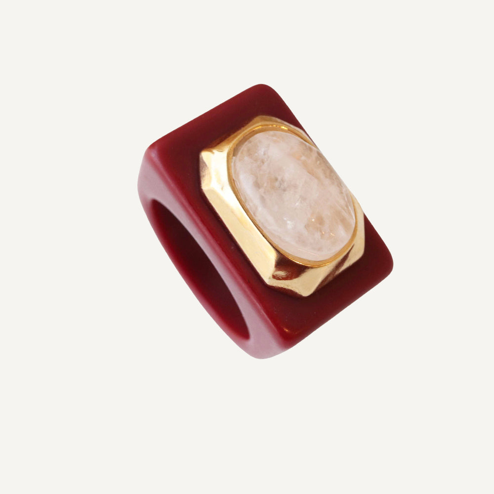 Anillo cuadrado de resina roja con piedra ovalada y detalle dorado. Ideal para un look moderno y elegante.