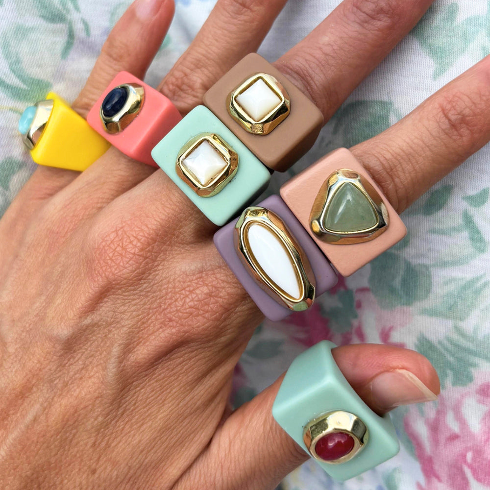 Anillos de silicona coloridos con piedras preciosas, estilo moderno y elegante, en tonos amarillo, verde y rosa.