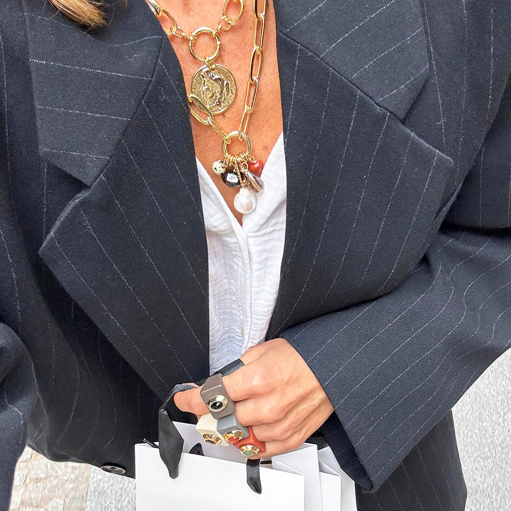 Chaqueta de rayas negra, collar dorado con perlas y accesorios, look moderno y elegante, ideal para ocasiones chic.