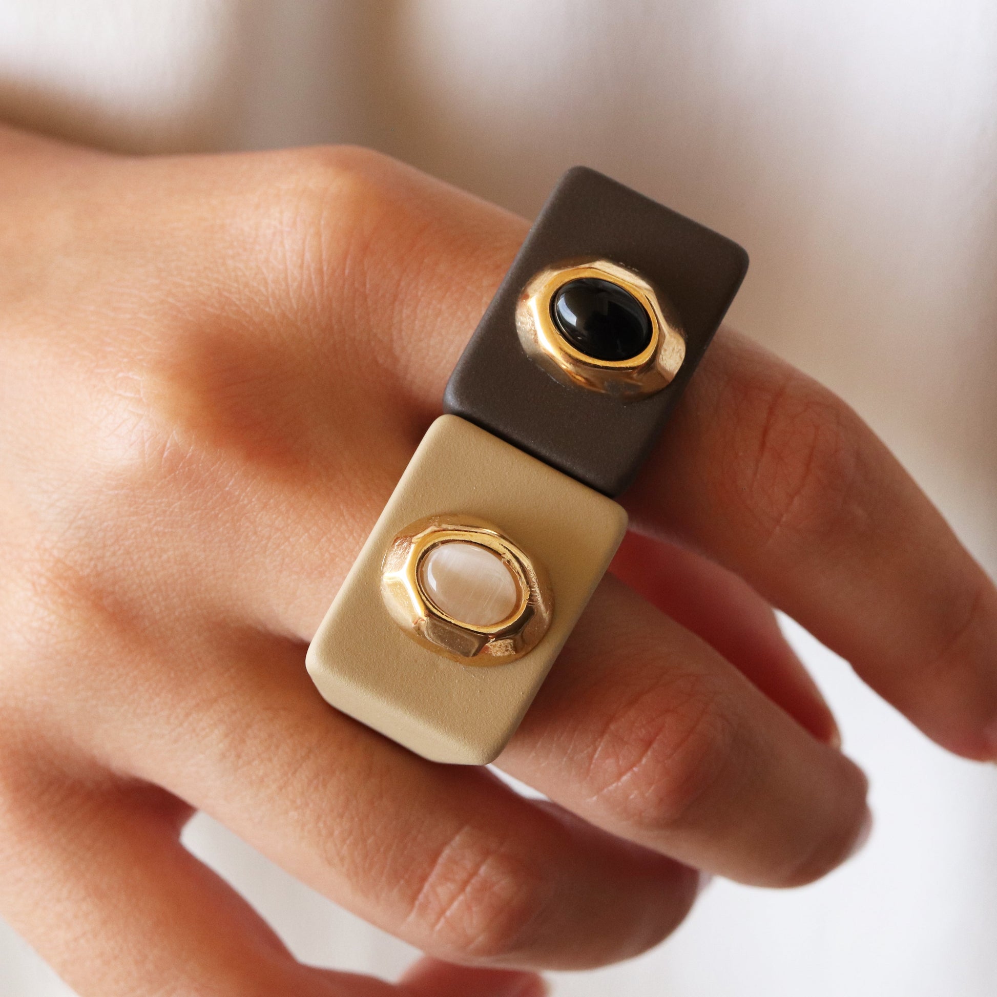 Anillo moderno bicolor en tonos marrón y beige, con gemas negras y blancas, estilo minimalista y elegante.