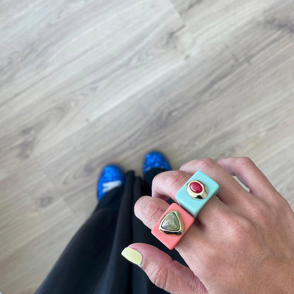 Anillo de dos piezas en colores coral y verde, con gemas en verde y rojo, estilo moderno y llamativo.