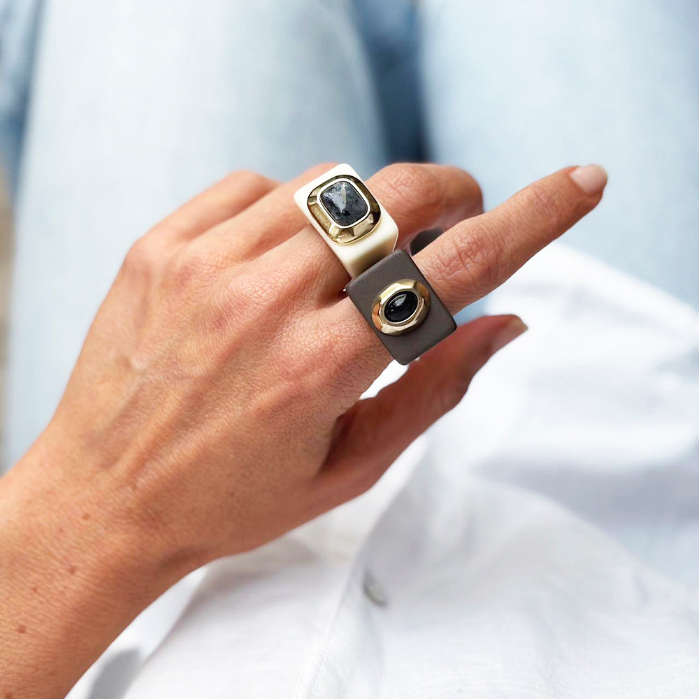 Anillo de moda en blanco y gris con gemas negras, estilo contemporáneo y minimalista.