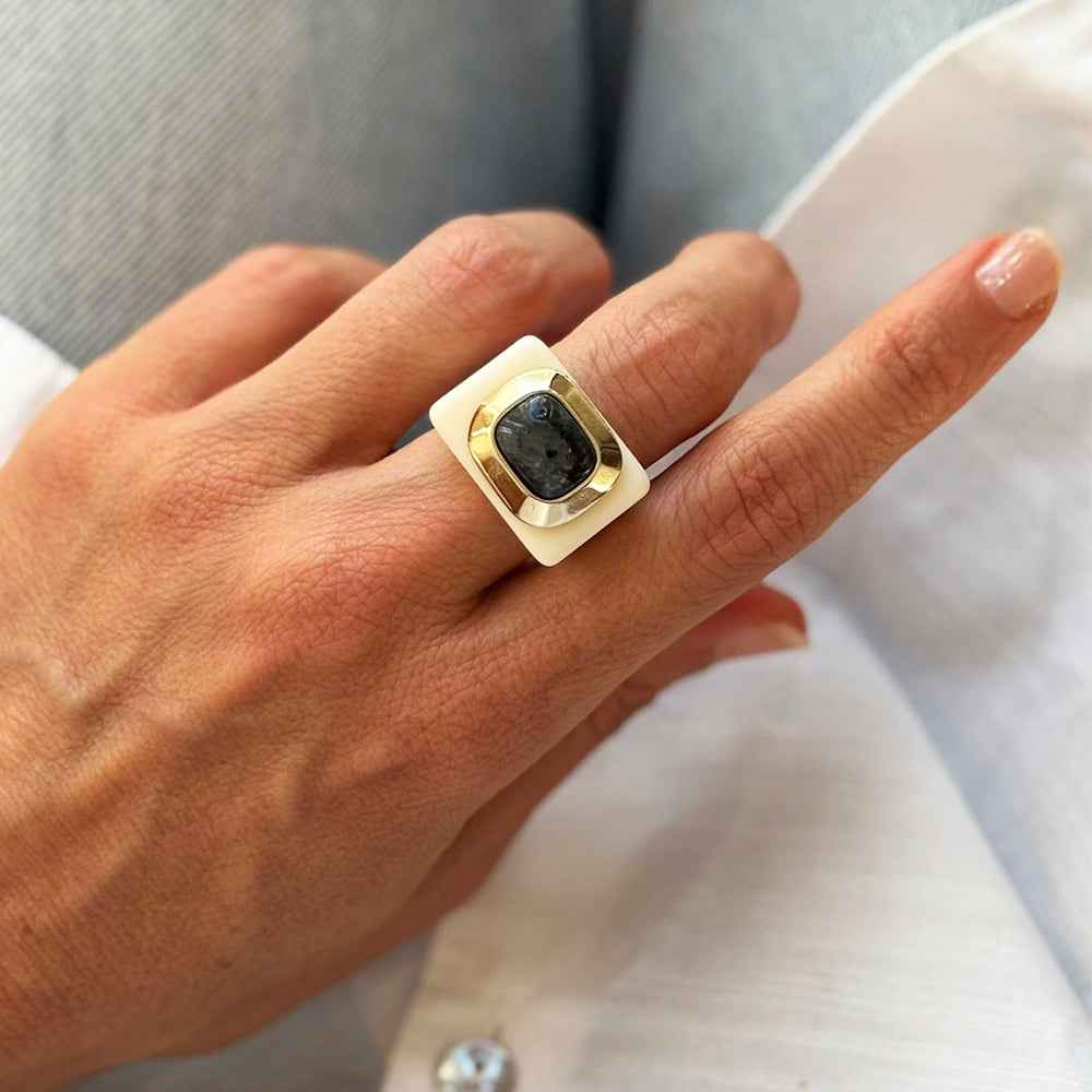 Anillo contemporáneo de metal dorado y piedra negra, diseño cuadrado, perfecto para un look elegante.