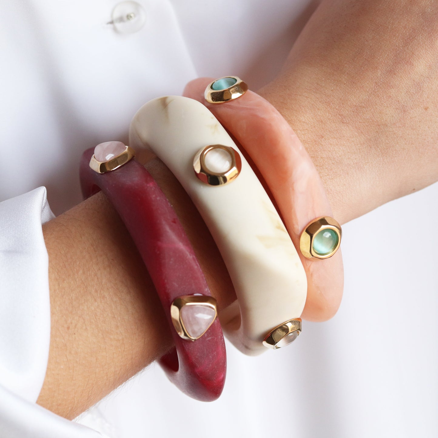 Brazaletes de resina en tonos rojo, blanco y rosa con detalles dorados, elegantes y modernos.