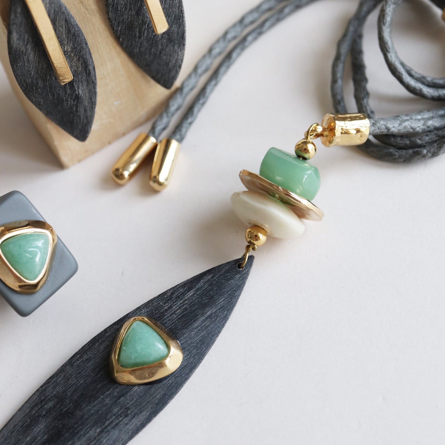 Collar moderno con colgante negro, piedras verdes y doradas, detalles elegantes en acero. Ideal para un look chic.