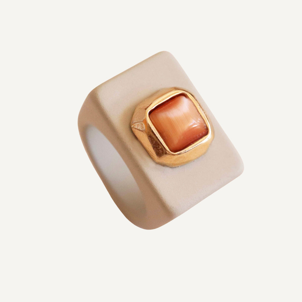 Anillo cuadrado beige con piedra naranja y detalle dorado, estilo moderno y elegante.