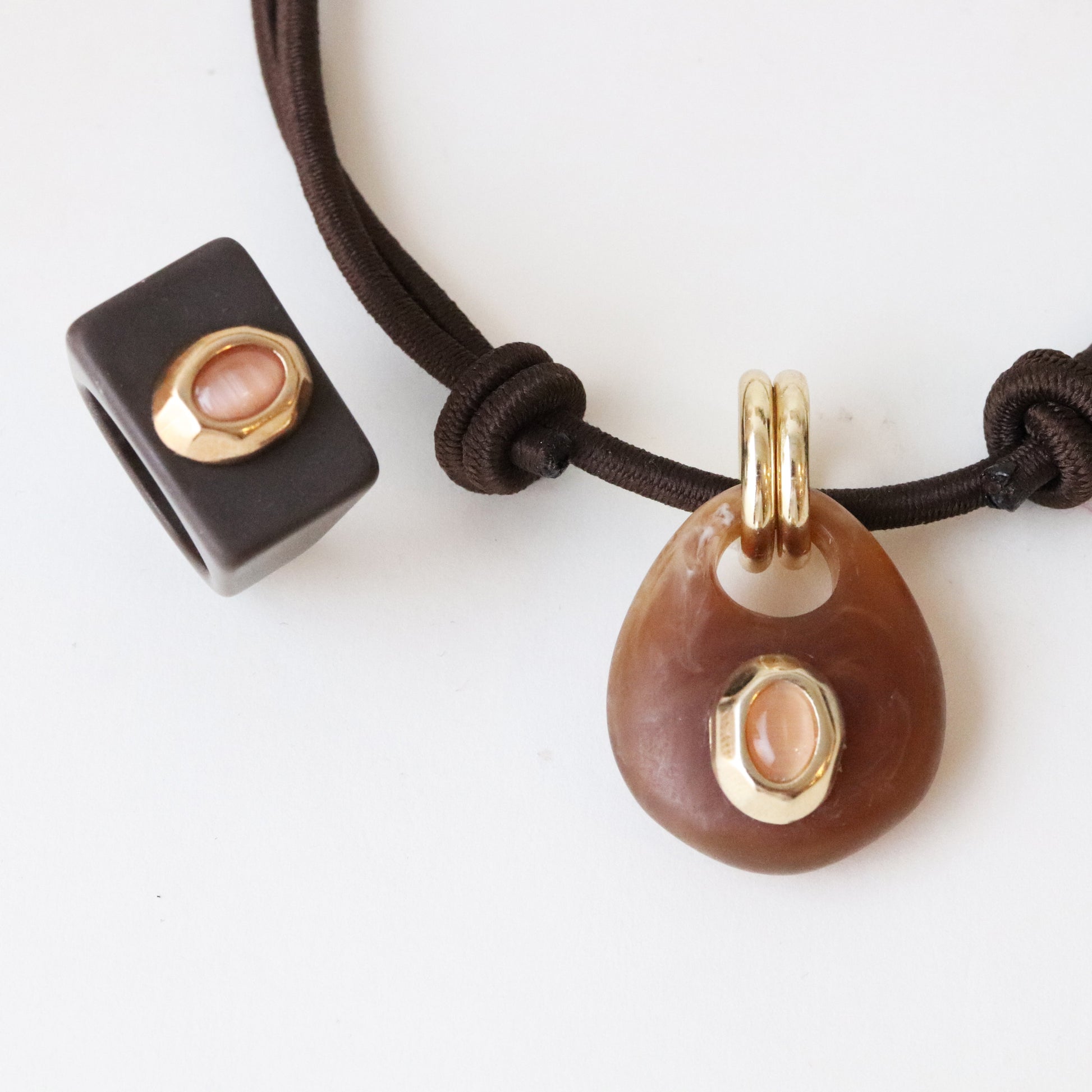 Collar de piedra marrón con detalle dorado y cuentas de cerámica negra en cordón ajustable.