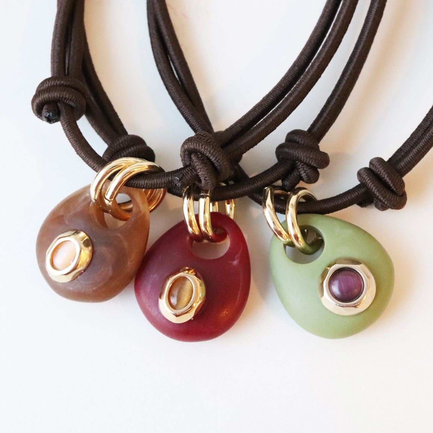 Collares de piedras en tonos marrón, rojo y verde con detalles en dorado, estilo bohemio y cordón marrón.