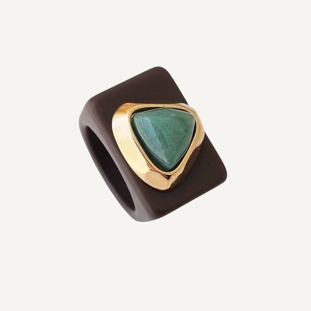 Anillo cuadrado marrón con piedra verde y montura dorada, estilo moderno y elegante.