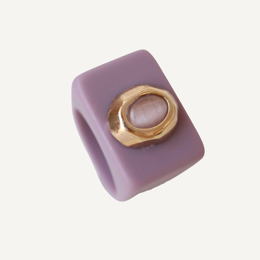 Anillo cuadrado de resina morada con gemas, detalle dorado brillante, estilo moderno y elegante.