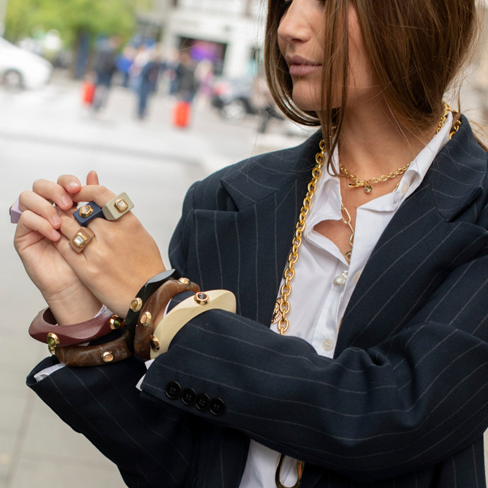 Conjunto de pulseras de acrílico y metal en tonos marrón, nude y dorado, con anillos a juego, estilo elegante y moderno.