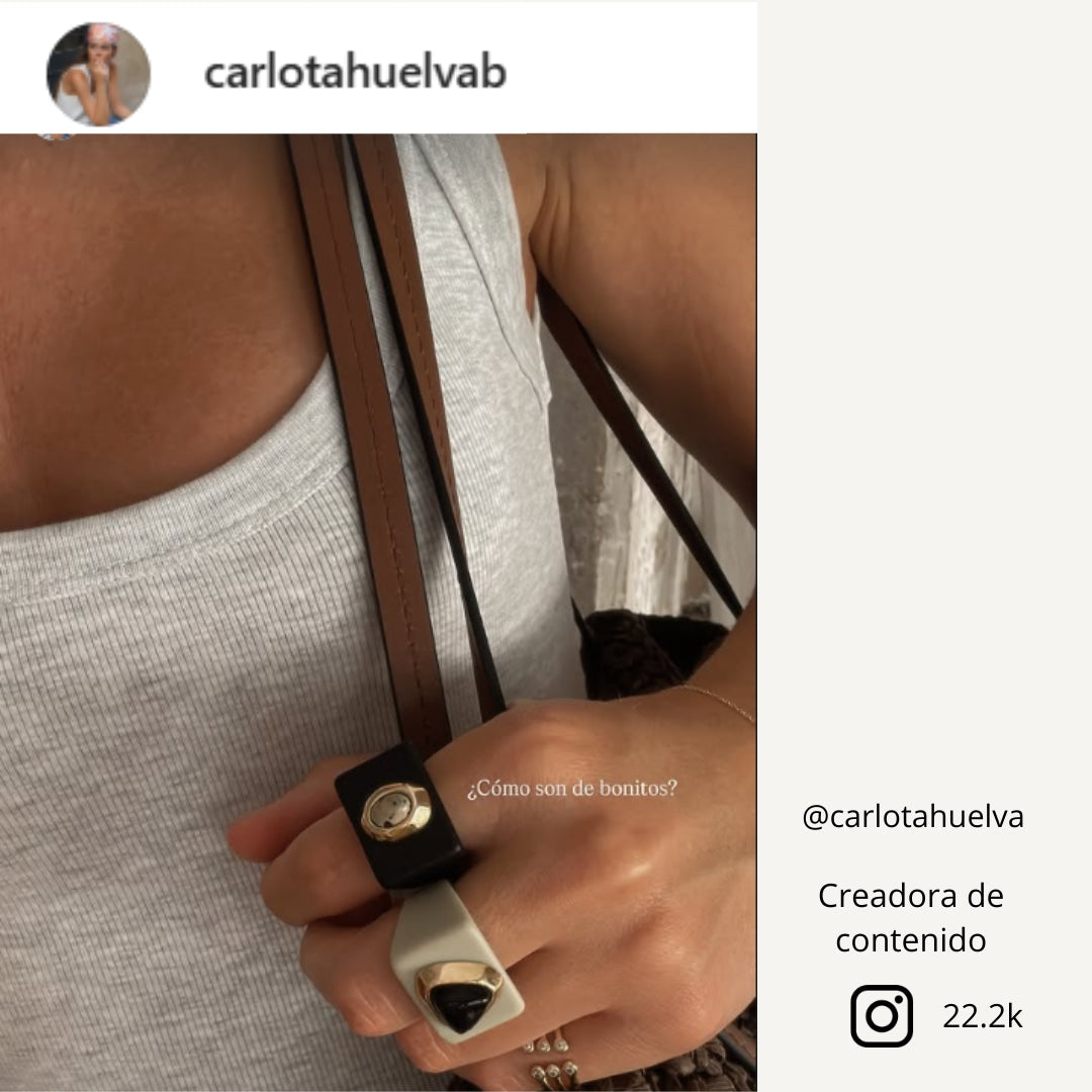 Anillo de resina blanca y negra, diseño moderno, con detalles brillantes y textura elegante.