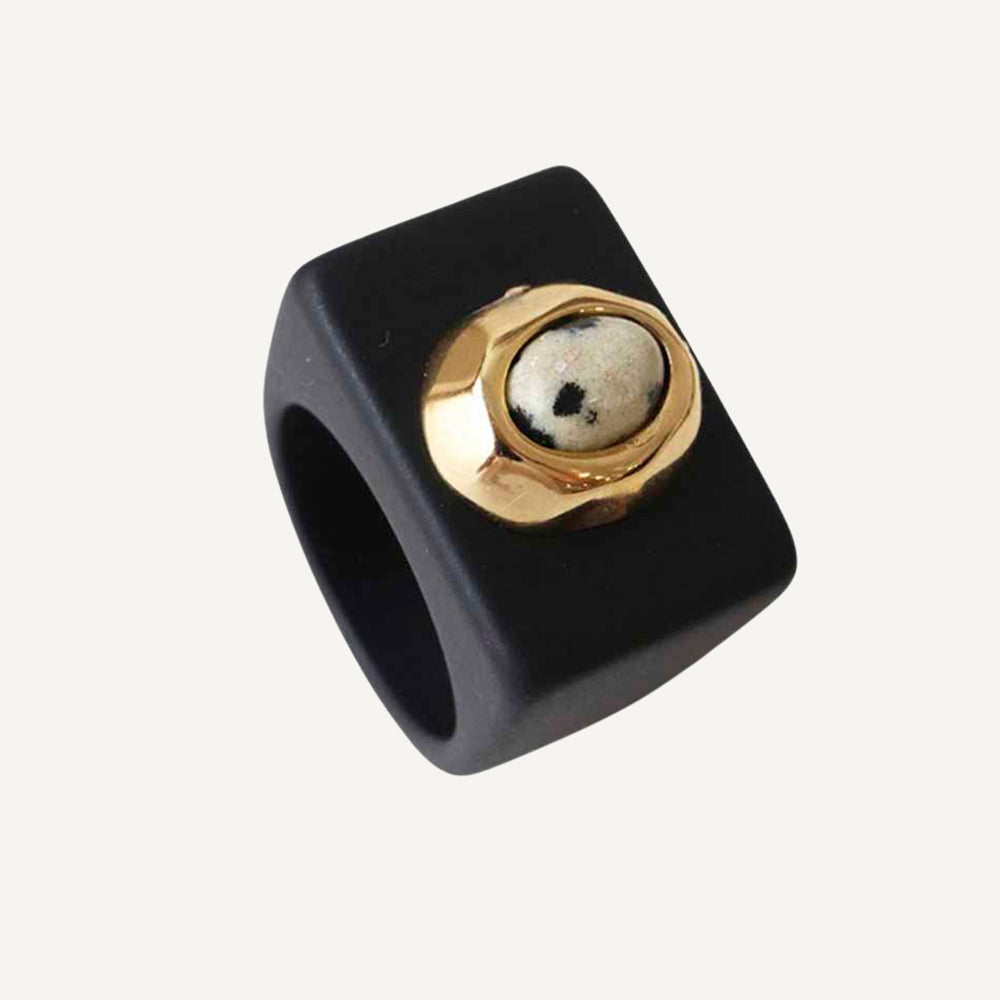 Anillo cuadrado de resina negra con piedra dorada en el centro, elegante y moderno.