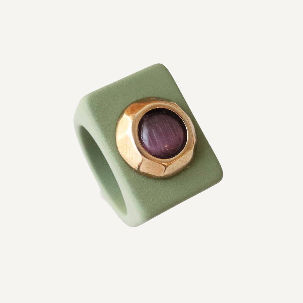 Anillo cuadrado de silicona verde con piedra morada y detalle dorado. Ideal para un estilo moderno y único.
