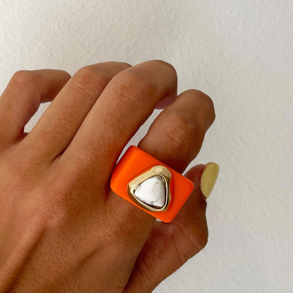 Anillo moderno de silicona naranja con detalle en metal dorado en forma de triángulo. Ideal para un estilo vanguardista.