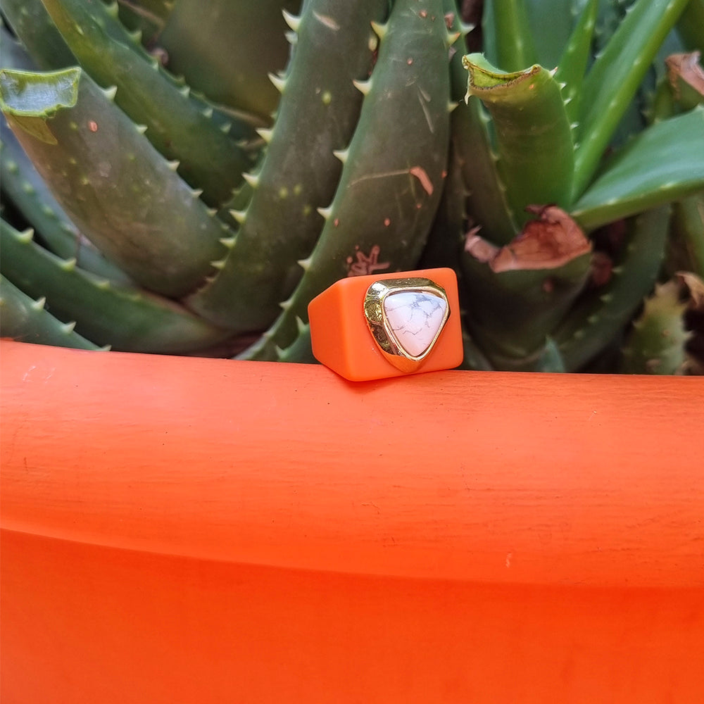 Anillo naranja de silicona con piedra blanca en forma de triángulo y detalle dorado. Ideal para un estilo moderno.