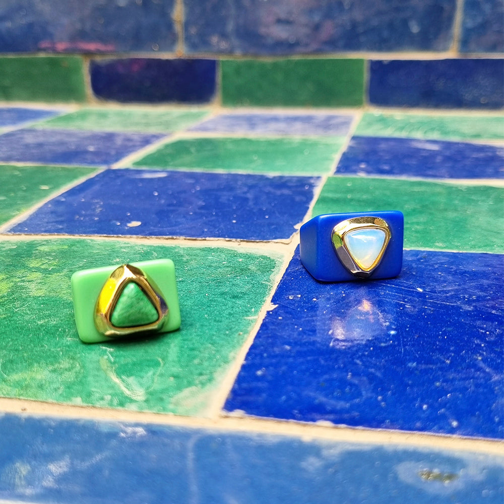 Anillos modernos de resina verde y azul con detalles dorados y piedras triangulares.