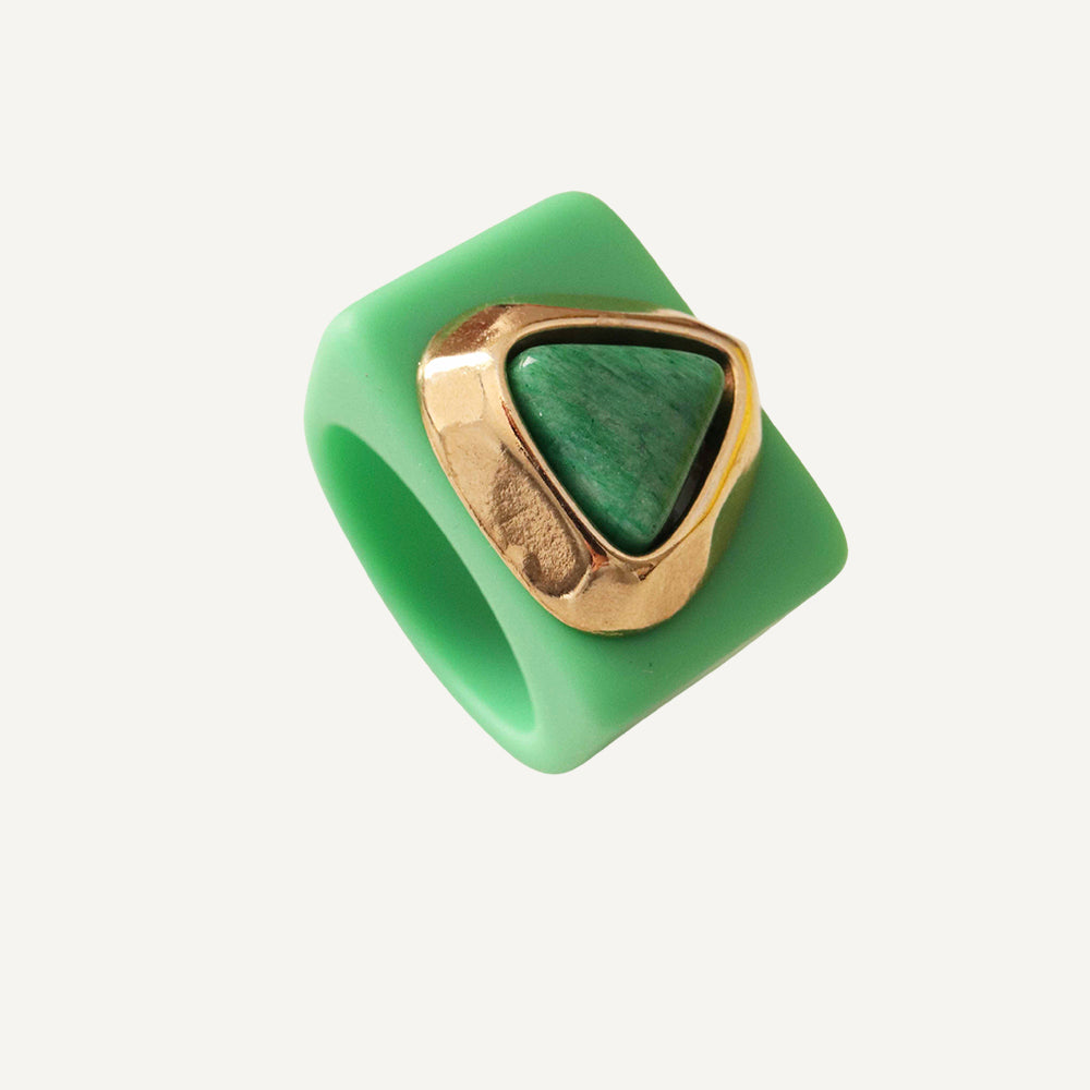 Anillo verde de silicona con detalle en oro y piedra verde, estilo moderno y sofisticado.