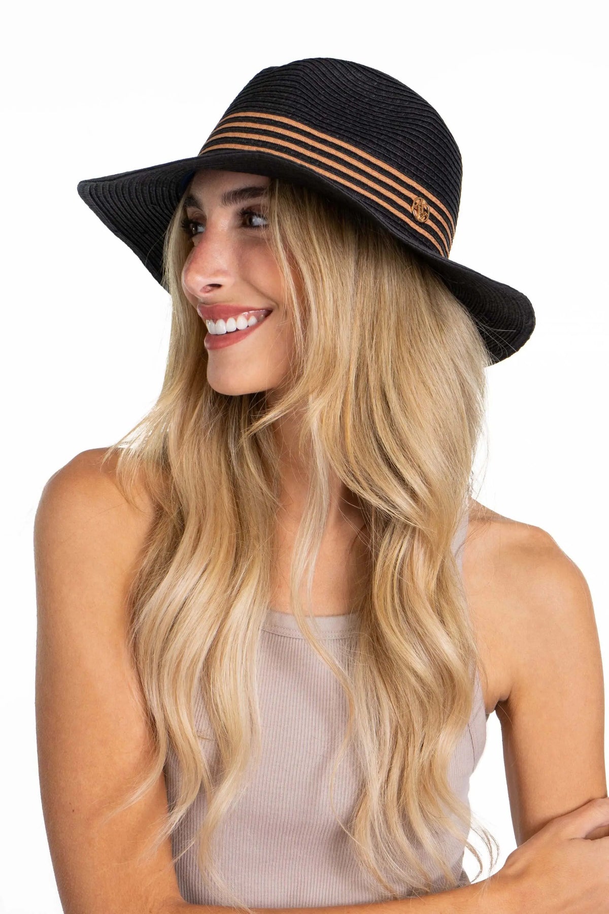 A blonde woman wears a black straw Panama hat with tan striped detail around the crown and a small metallic logo.