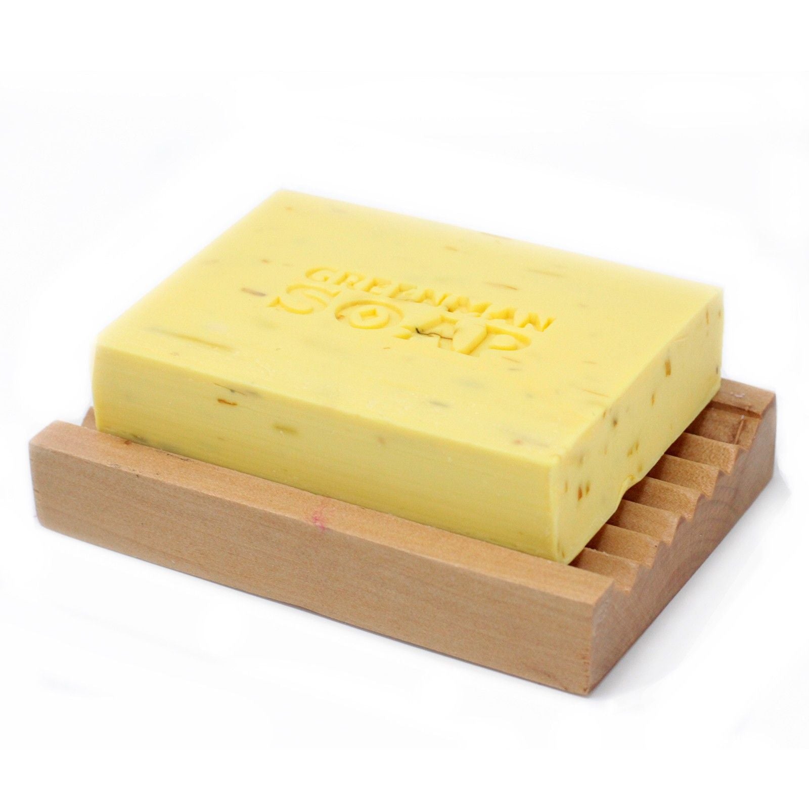 Jabón rectangular amarillo con textura, marcado "GREENMAN SOAP", sobre una jabonera de madera acanalada. Fondo blanco.