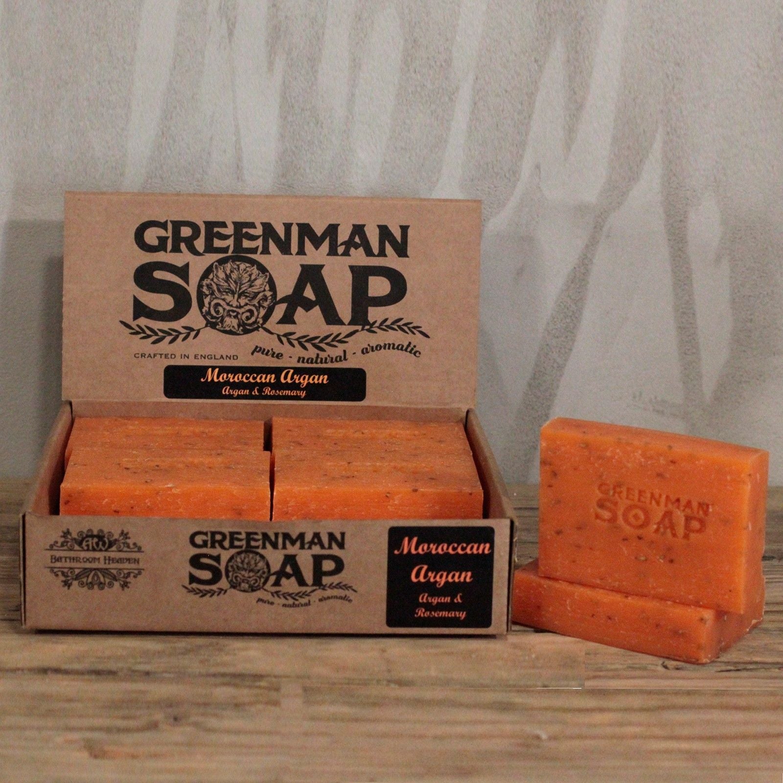Caja de cartón con jabones naranja texturizados de argán Greenman. Logo de rostro natural y estilo rústico artesanal.