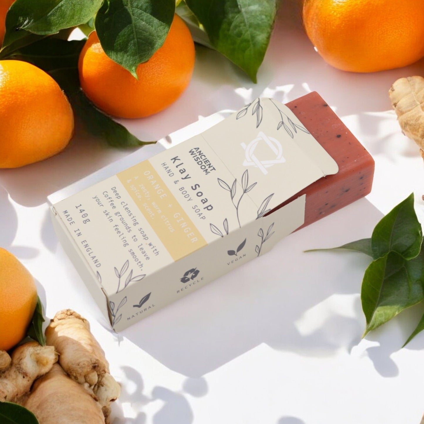 Jabón artesanal de naranja y jengibre, color naranja con envoltura blanca y diseño elegante. 140 g. Hecho en Inglaterra.