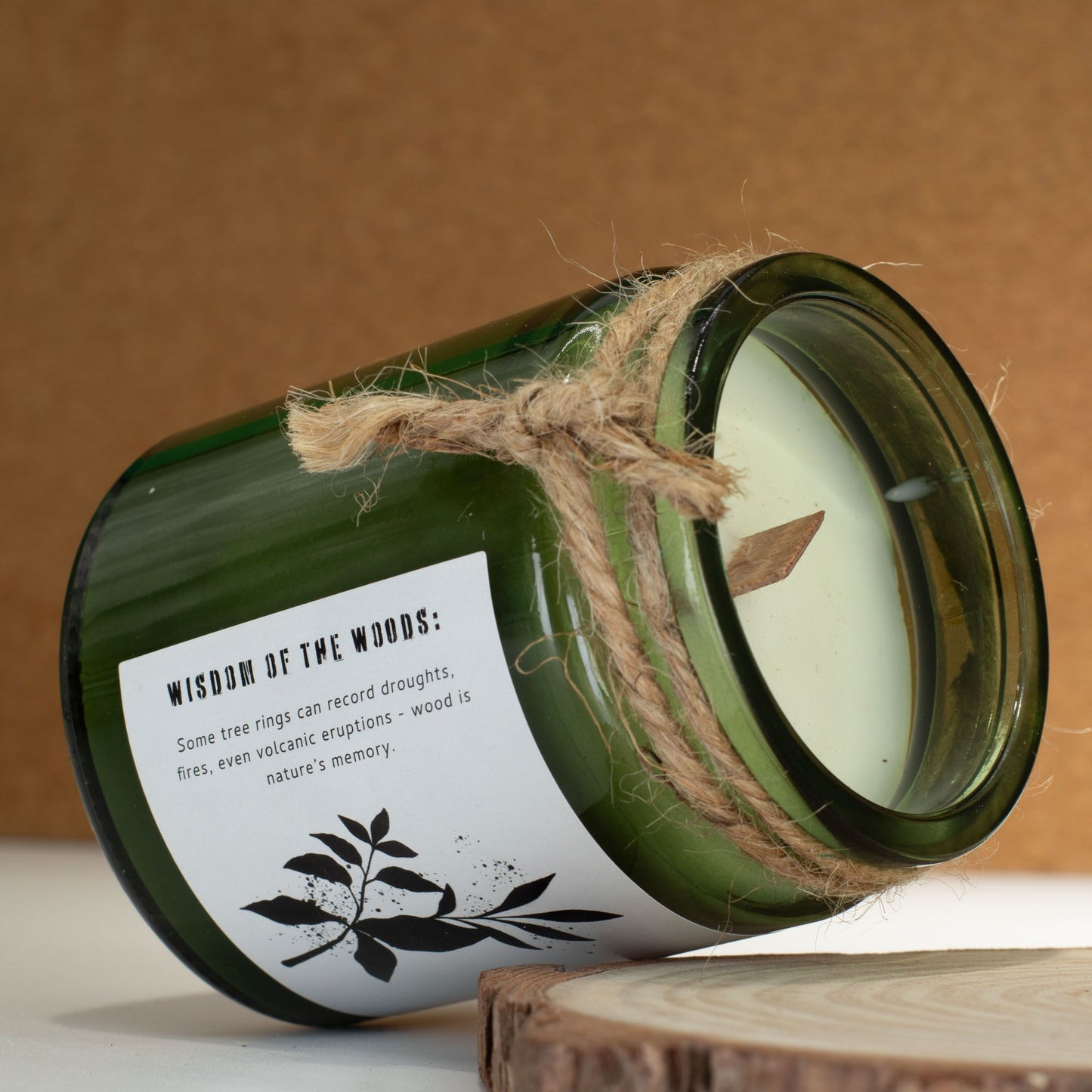 Vela aromática verde en frasco de vidrio, con etiqueta blanca y cuerda, estilo rústico y natural.