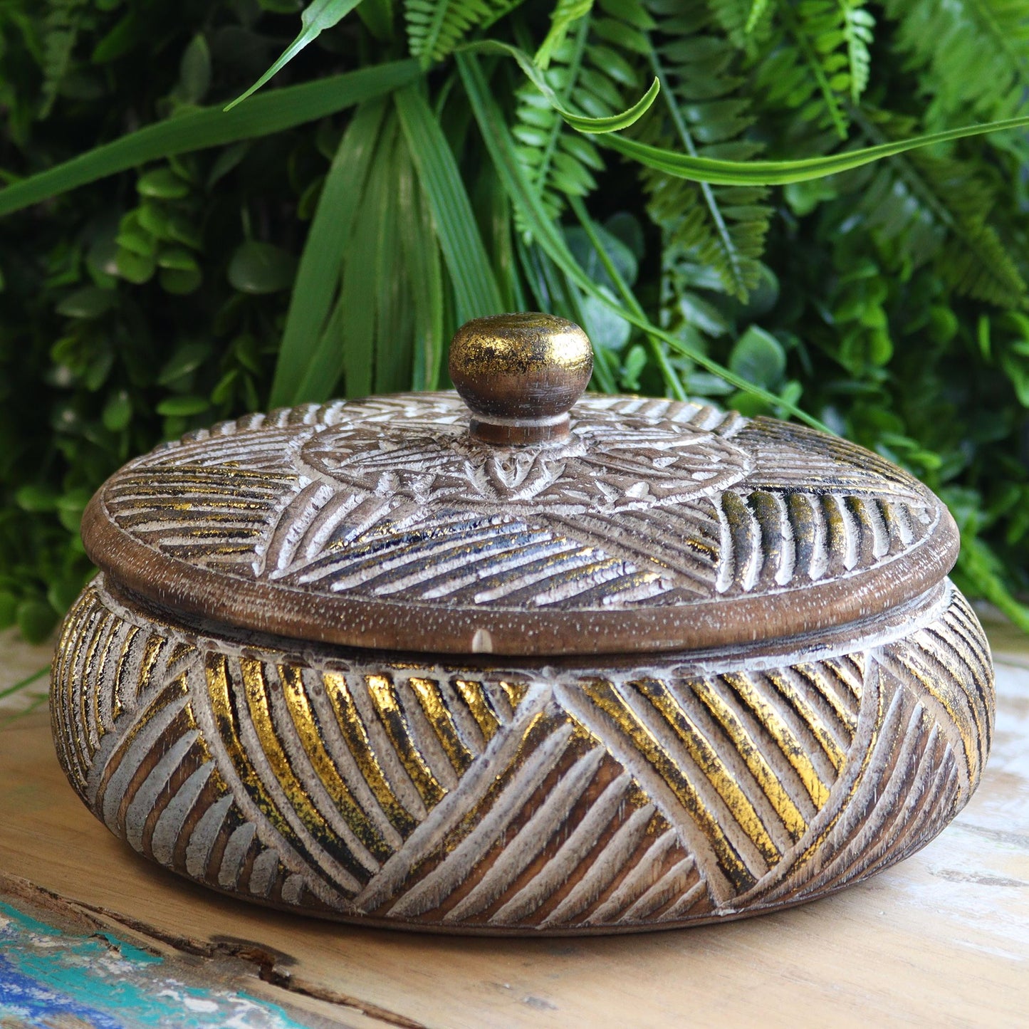 Caja decorativa redonda de madera en tonos marrón y dorado con diseño de hojas. Ideal para almacenamiento y decoración