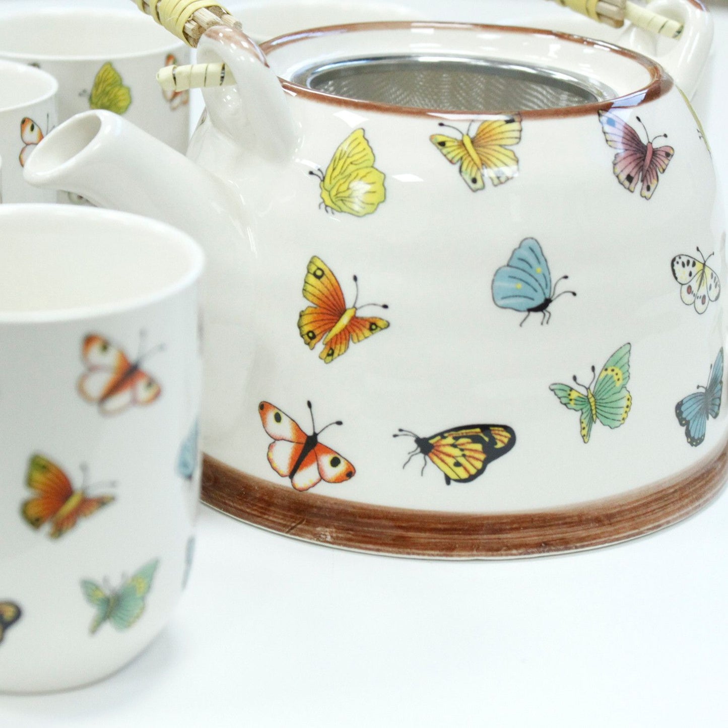 Tetera de cerámica blanca con mariposas de colores y juego de tazas a juego. Ideal para té y decoración.