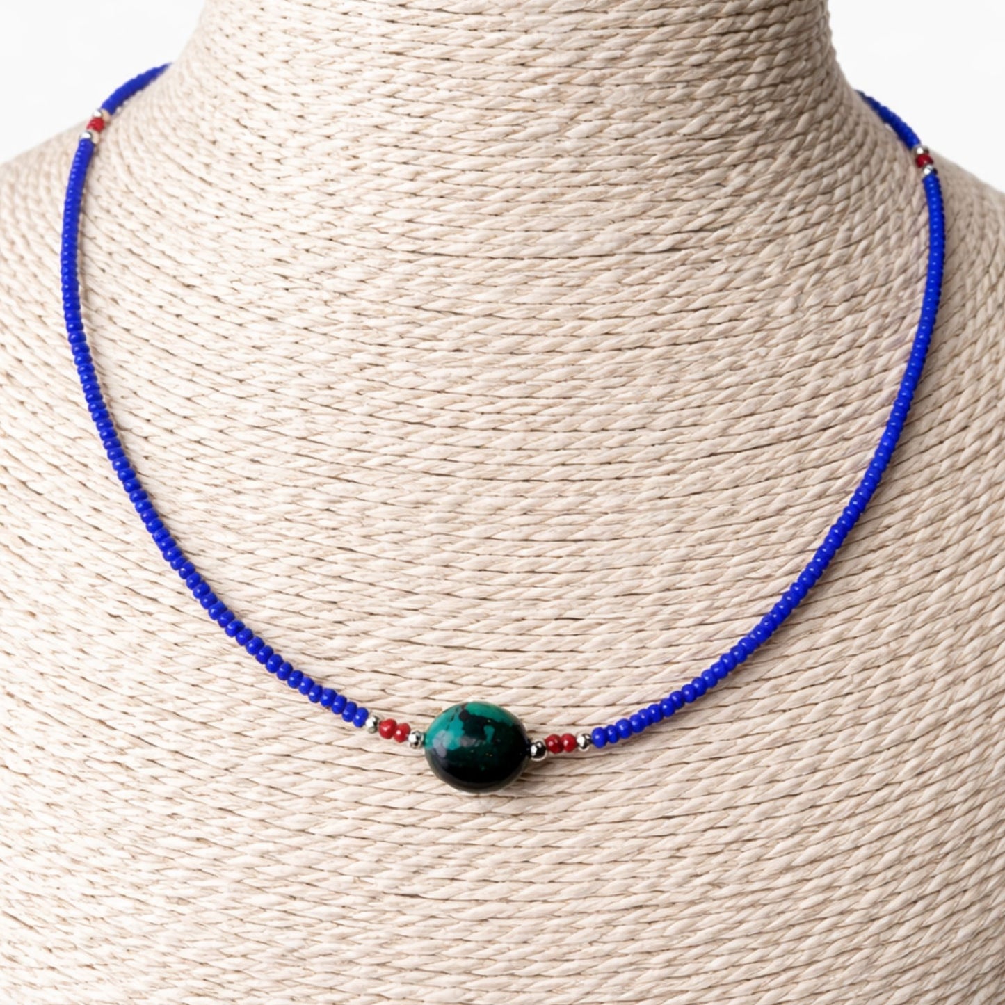 Collar de cuentas azules y rojas con un ópalo verde, estilo bohemio, ideal para ocasiones casuales.