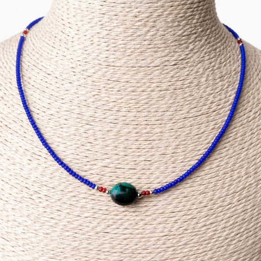 Collar de cuentas azules y rojas con un ópalo verde, estilo bohemio, ideal para ocasiones casuales.