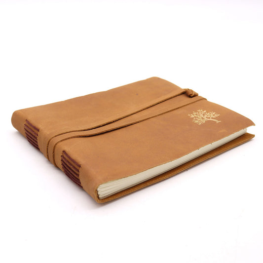 Cuaderno de cuero marrón de 18x23cm, con cierre de tira, encuadernación artesanal y grabado de árbol en la portada.