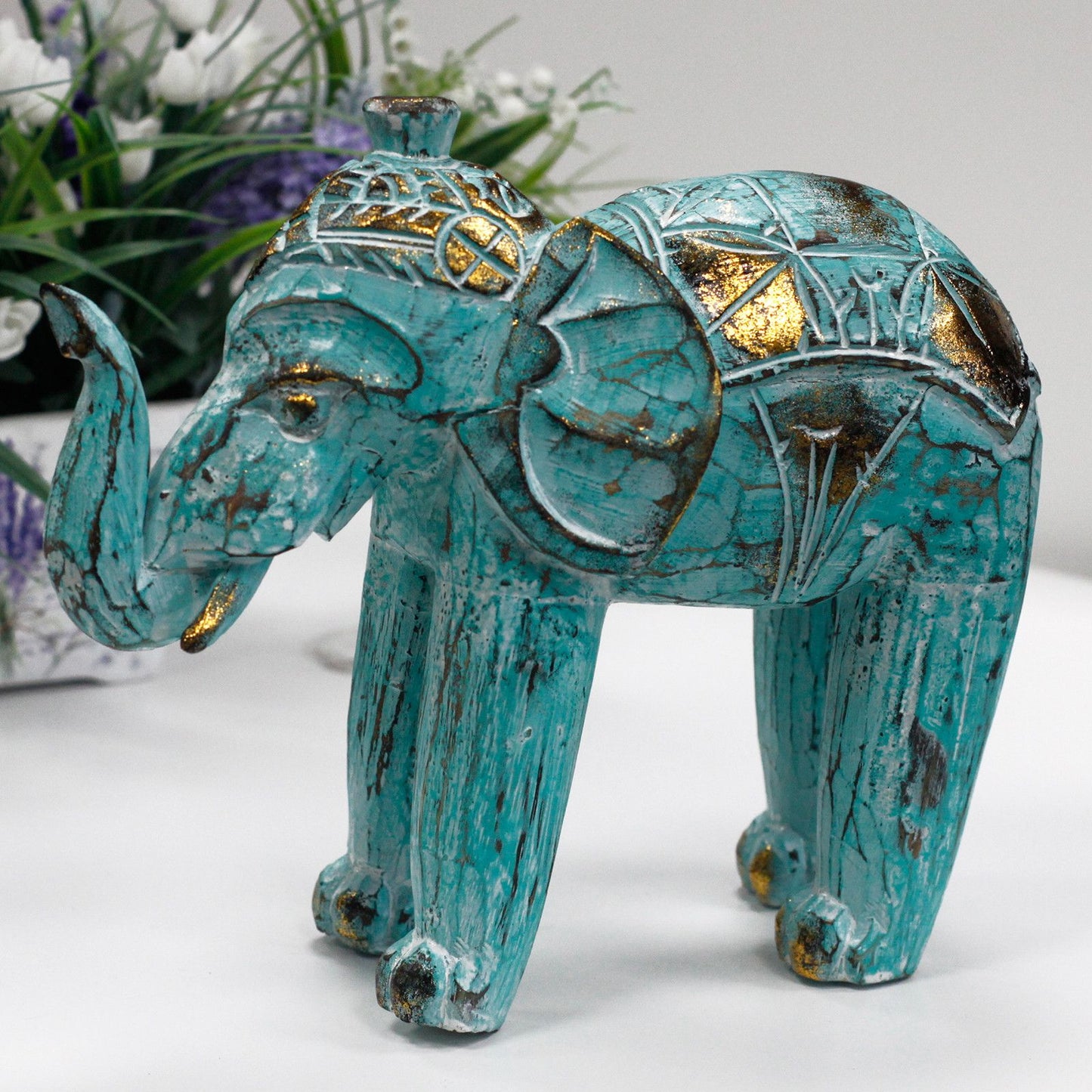Elefante decorativo de cerámica turquesa con detalles dorados y estilo étnico. Ideal para decoración del hogar.