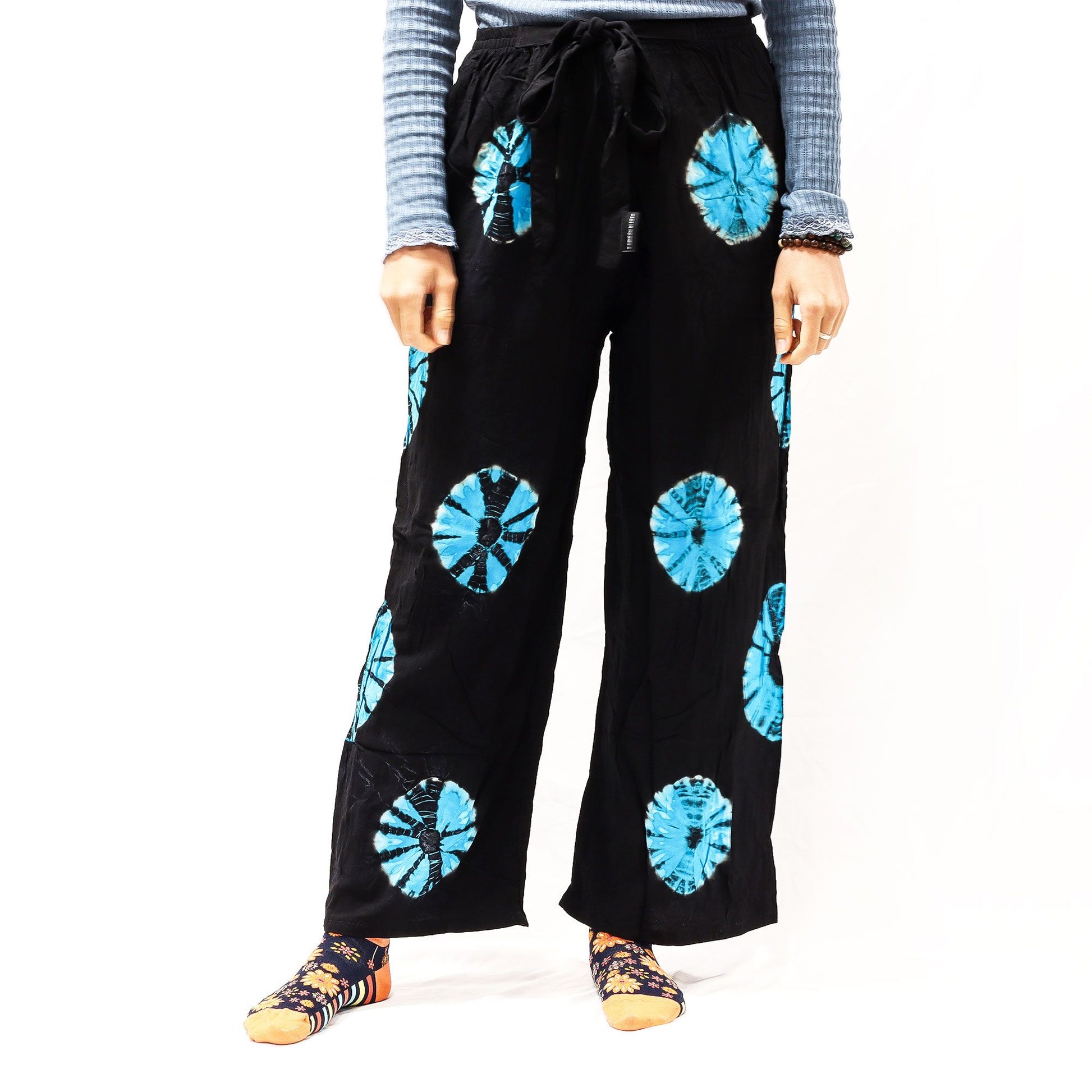 Pantalones de descanso negros de corte holgado con estampado circular azul, cintura elástica y cordón ajustable.