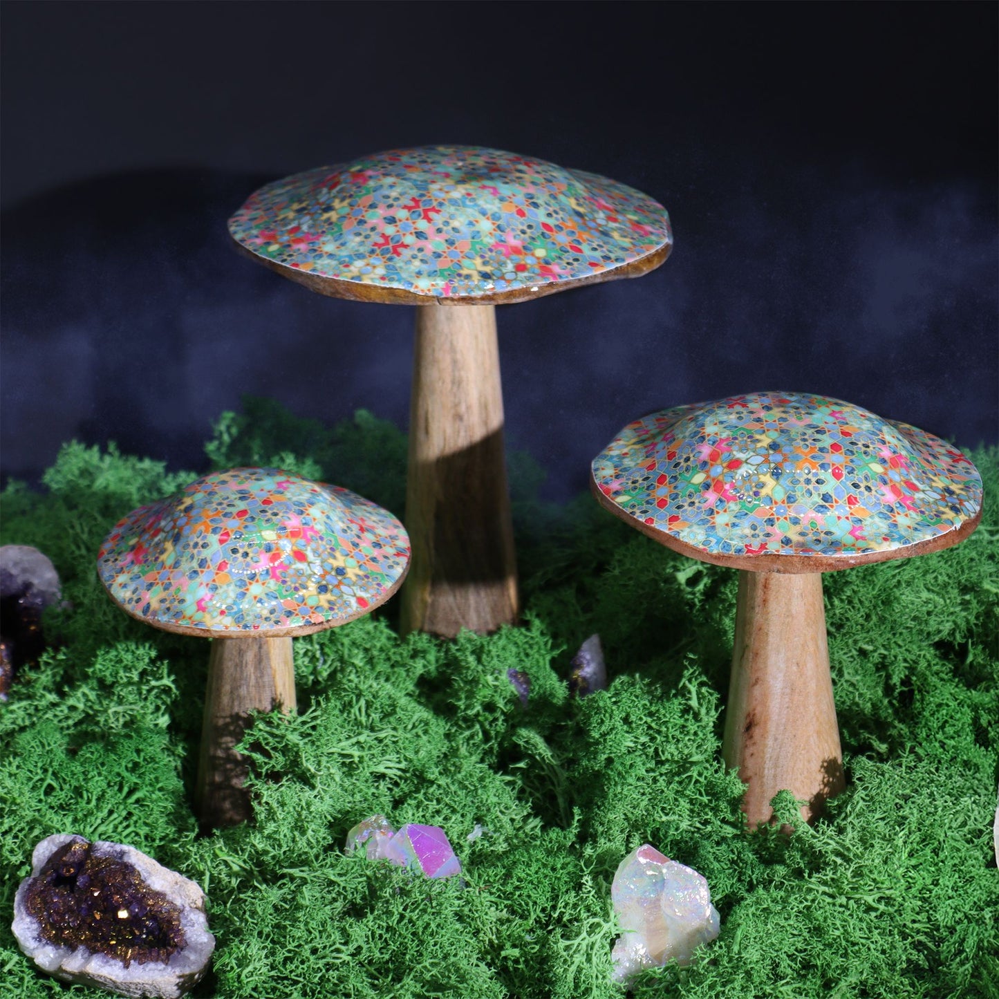 Set de hongos decorativos de madera, con sombreros de colores brillantes y base rústica, sobre musgo verde.