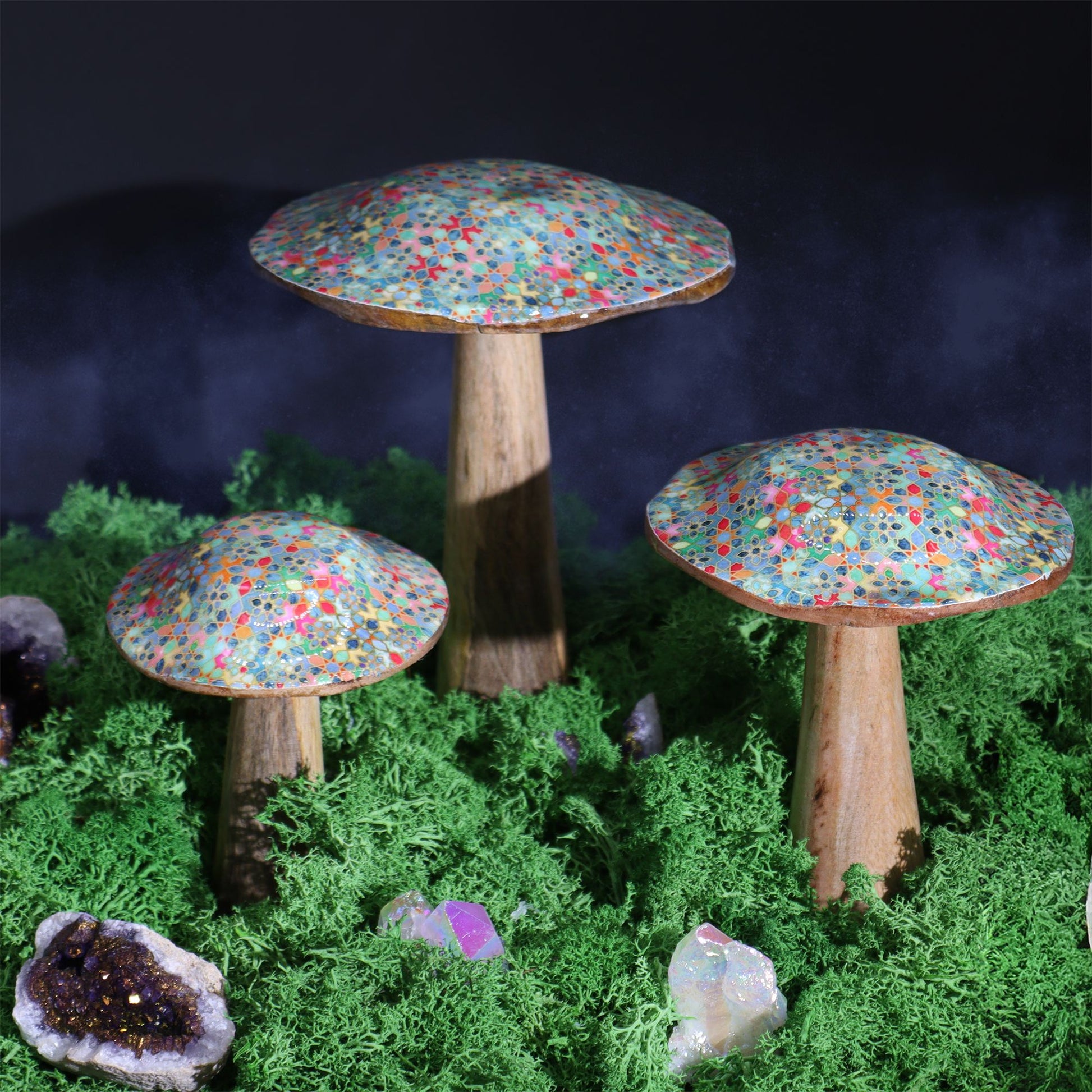 Set de hongos decorativos de madera, con sombreros de colores brillantes y base rústica, sobre musgo verde.