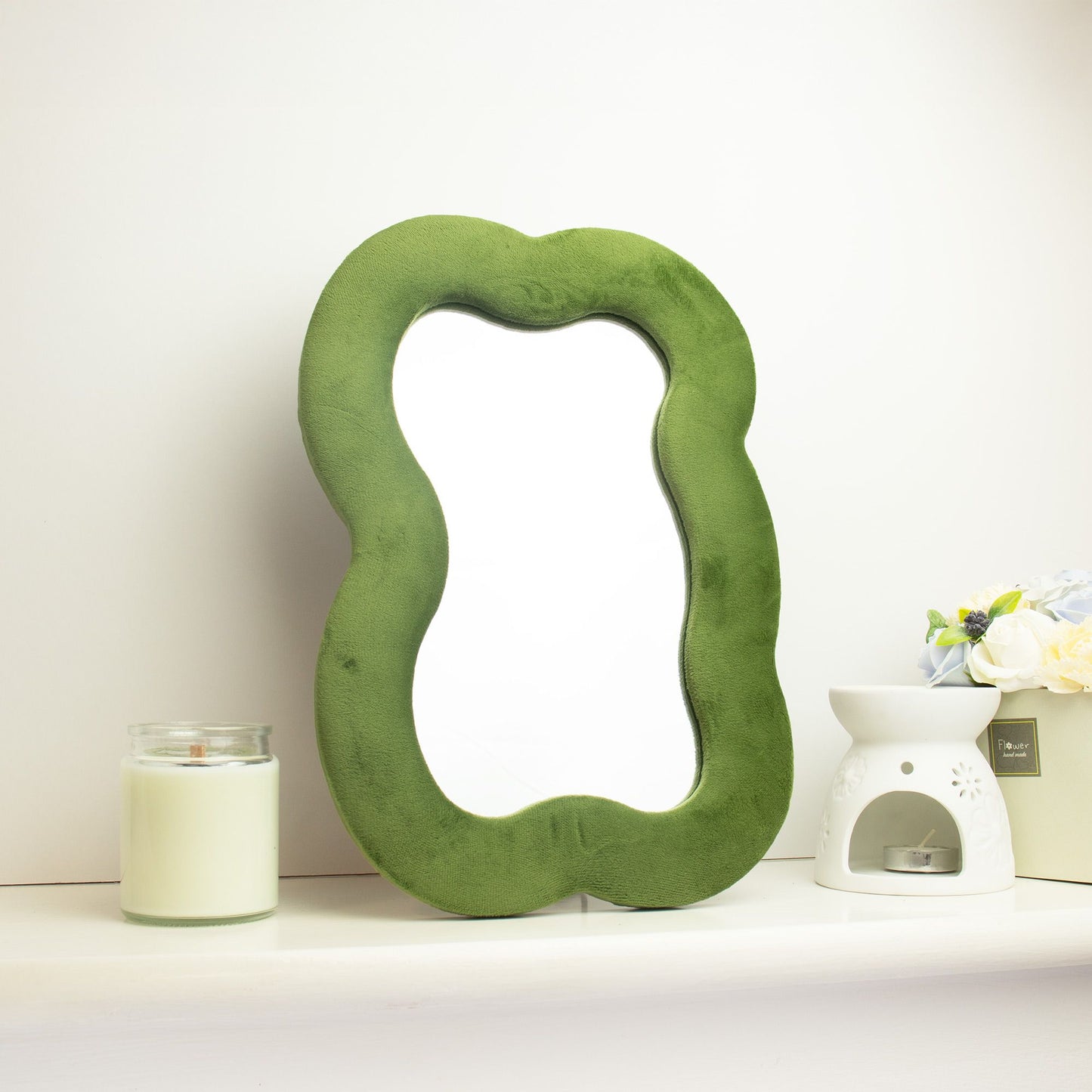 Espejo decorativo verde en forma orgánica con marco de terciopelo, ideal para cualquier ambiente moderno y elegante.
